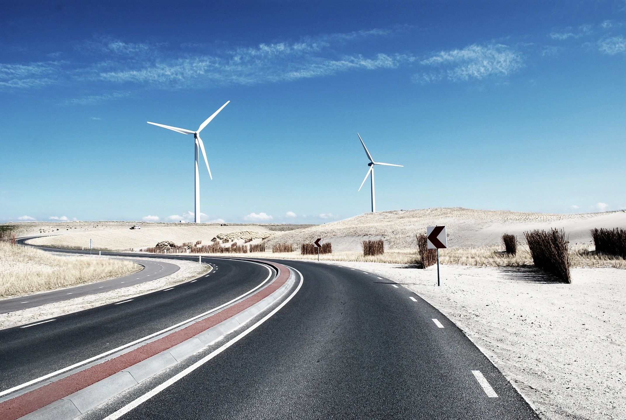 A pain straight road surrounded with a desert and some fan